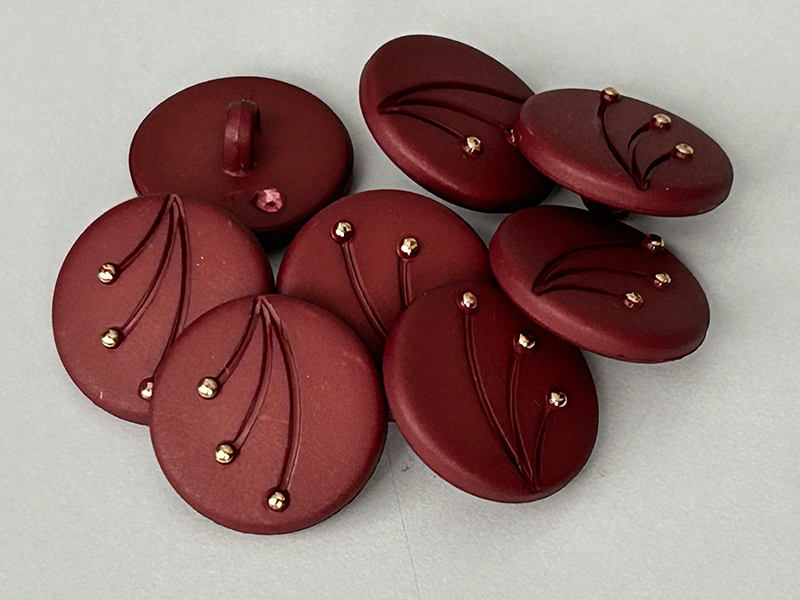 Rötlich-braune Kunststoffknöpfe mit goldfarbenen Details