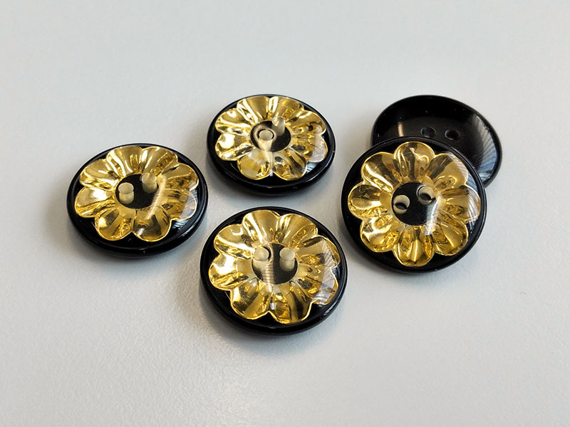 www.knopfparadies.de - 6134gs - Schwarz-goldfarbene Kunststoffknöpfe mit Blüte