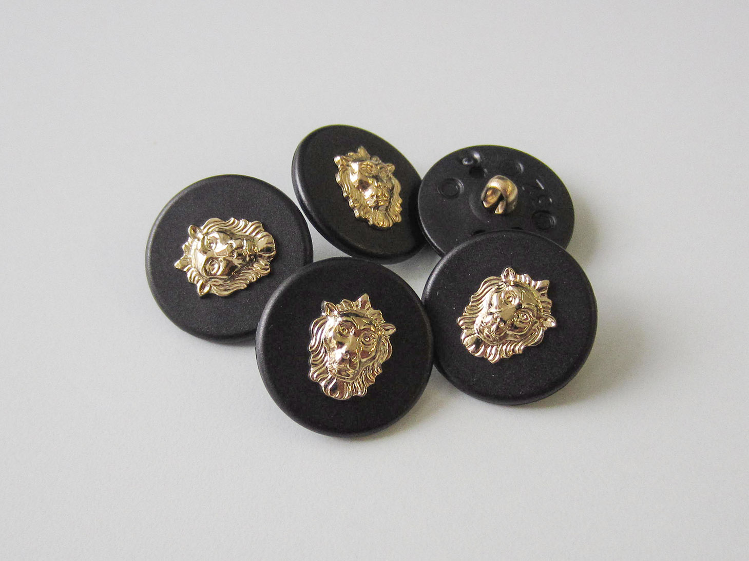 Eleganter schwarzer Ösen Knopf mit goldfb. Löwen Kopf