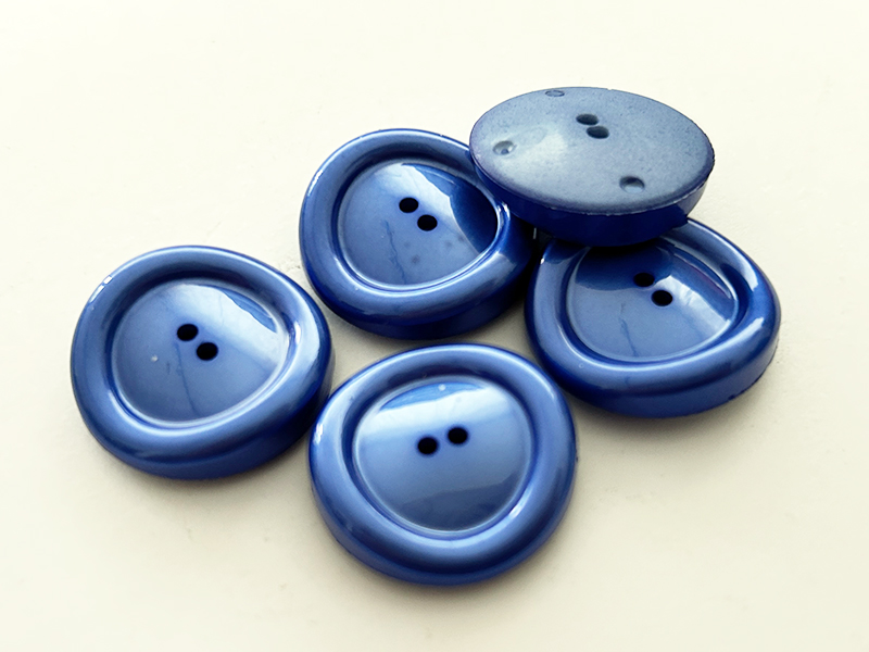 Blaue Kunststoffknöpfe mit schimmerndem Finish und besonderer Form