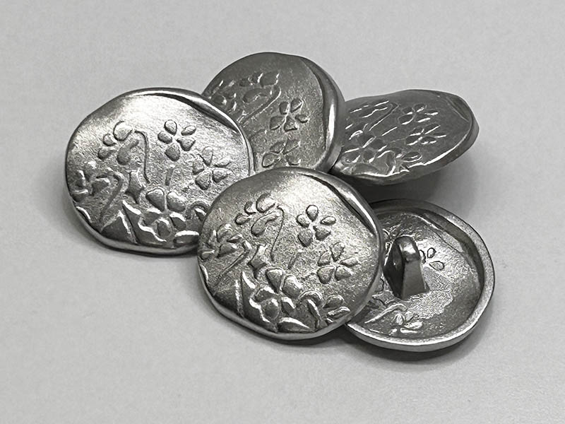Verspielte, unrunde Metallknöpfe in Silber mit Blumenmotiv und Ösenbefestigung