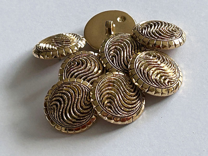 Goldfarbene Kunststoffknöpfe mit dreidimensionalem Wellen Design