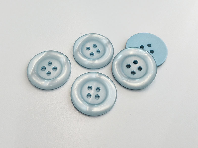 Blass hellblau schimmernde Kunststoffknöpfe mit vier Löchern und breitem Rand