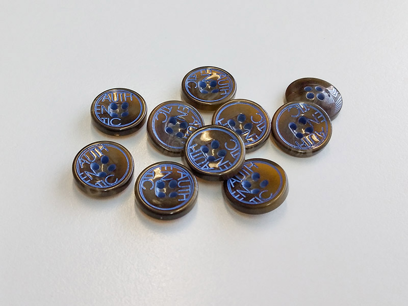Runder Blusenknopf in Hornoptik mit blauer AUTHENTIC-Prägung – 4-Loch