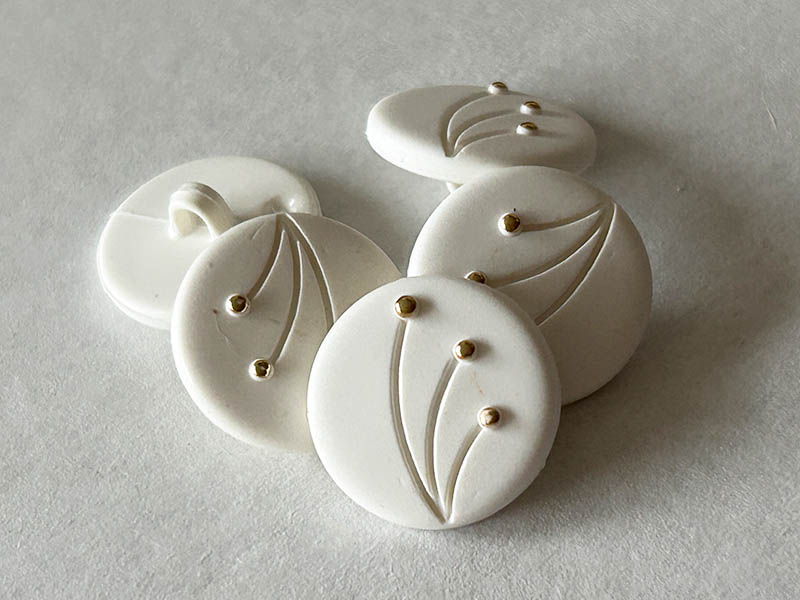 Elegante weiße Kunststoffknöpfe mit Goldakzenten