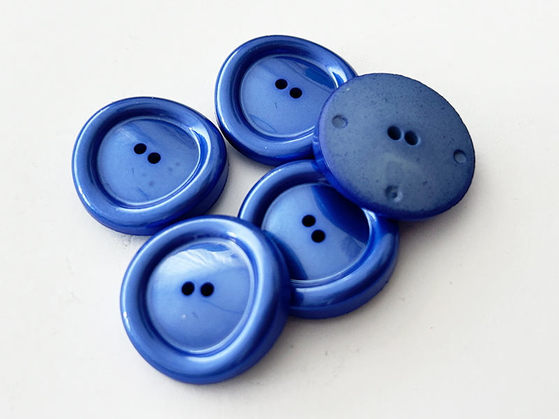 Blaue Kunststoffknöpfe mit schimmerndem Finish und besonderer Form