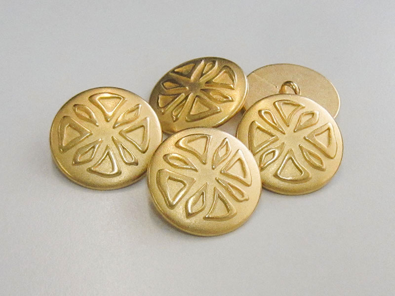 Goldfarbener Metallknopf mit Fantasiemuster