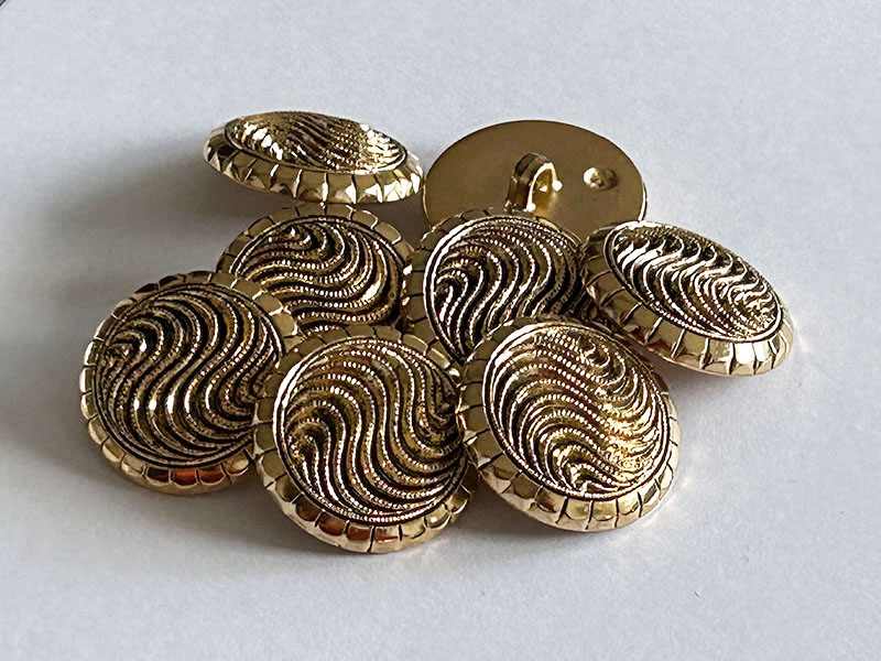 Goldfarbene Kunststoffknöpfe mit dreidimensionalem Wellen Design