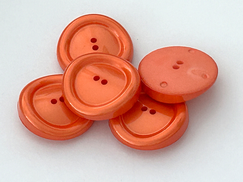 Schillernde orangefarbene Kunststoffknöpfe in besonderer Form