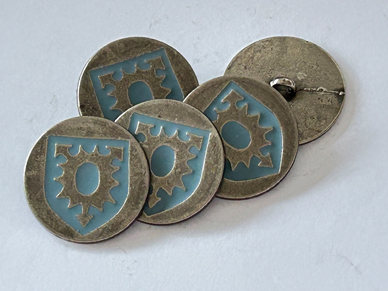 Interessanter Trachtenknopf in Altsilber mit taubenblauem Wappen