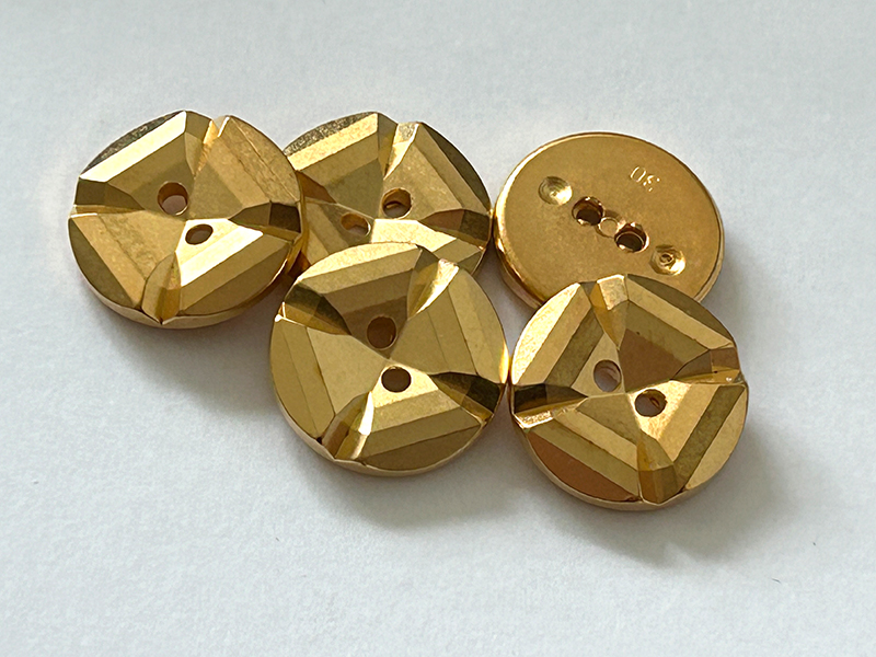 Goldfarbener Kunststoffknopf mit facettenartigem Treppendesign