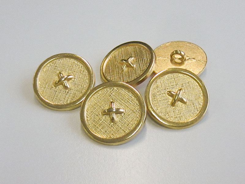 Goldfarbener Metallknopf mit Textilstruktur