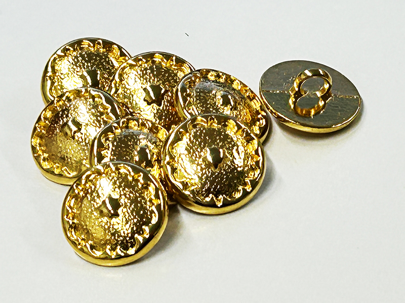 Glänzend goldfarbene Metallknöpfe mit strukturierter Oberfläche