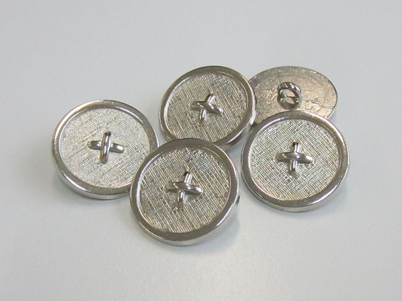 Silberfarbener Metallknopf mit Textilstruktur