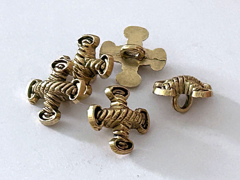 Altgoldfarbene Metallknöpfe mit gekreuzten Zierelementen