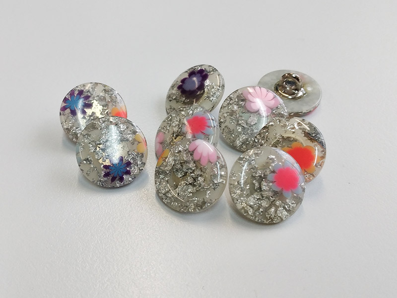 Ausgefallen schöne Ösenknöpfe mit glitzernden Einschlüssen und kleinen Blüten