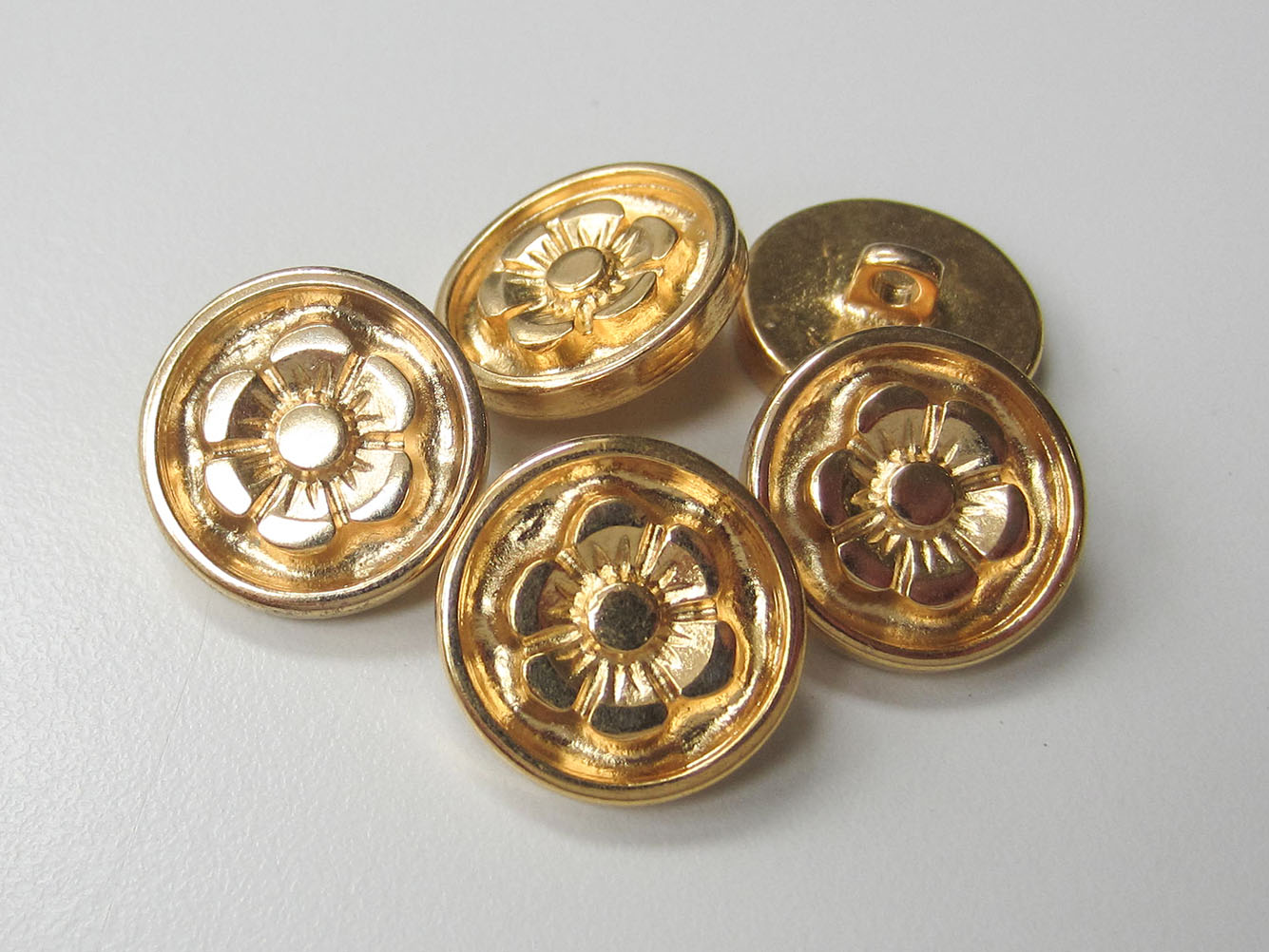 Goldfarbener Metallknopf mit Blüte