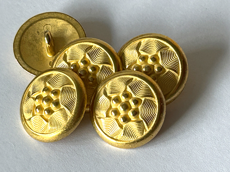 Goldfarbene Metallknöpfe mit detailreichem Blütenmuster