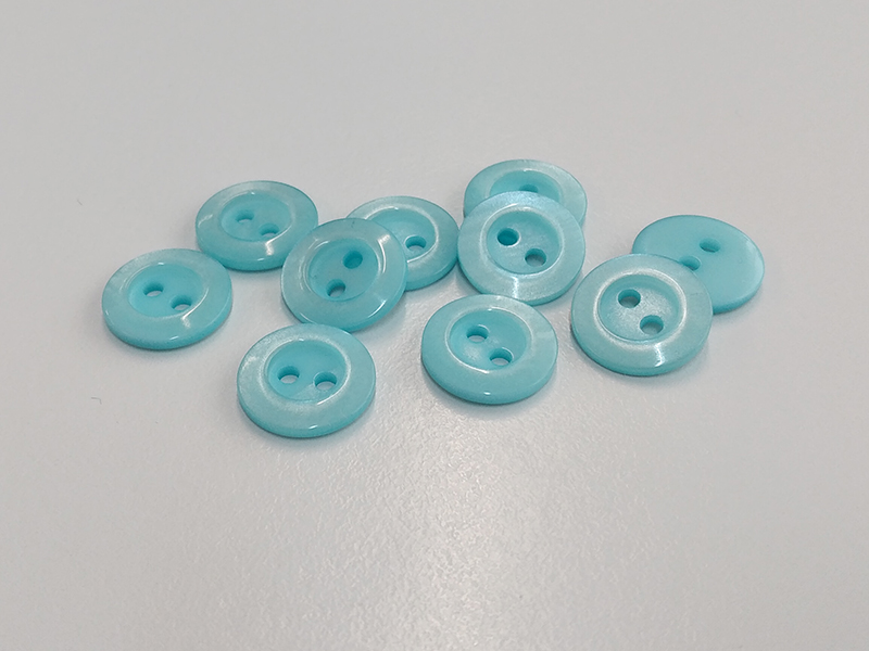 Hübsche kleine hellblau schimmernde Blusenknöpfe aus Kunststoff mit breitem Rand
