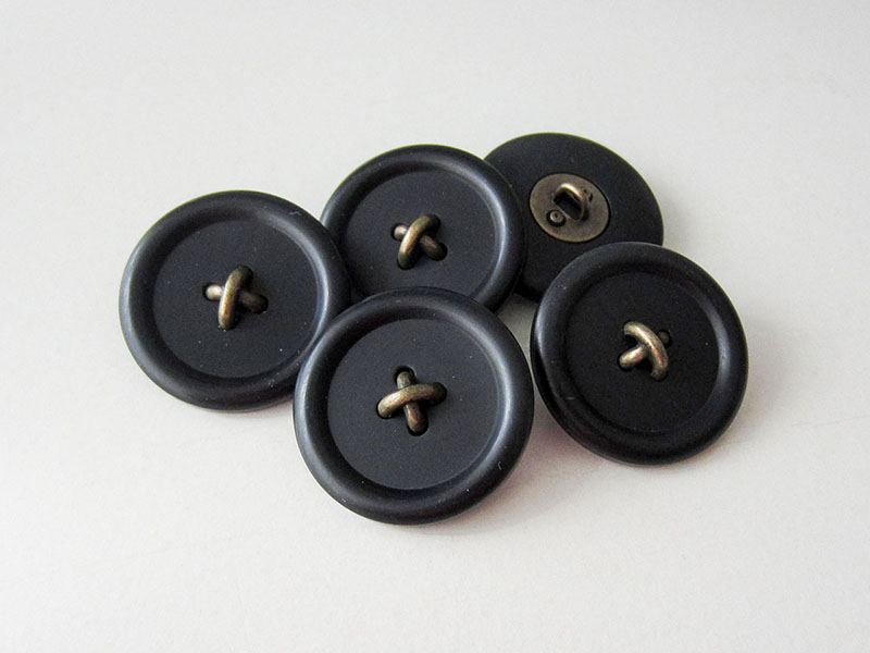 Kunststoffknopf in Schwarz mit messingfarbener Metall Applikation