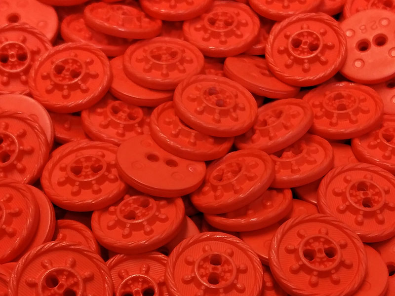 Neon-orange-rote Kunststoffknöpfe mit Steuerrad-Motiv