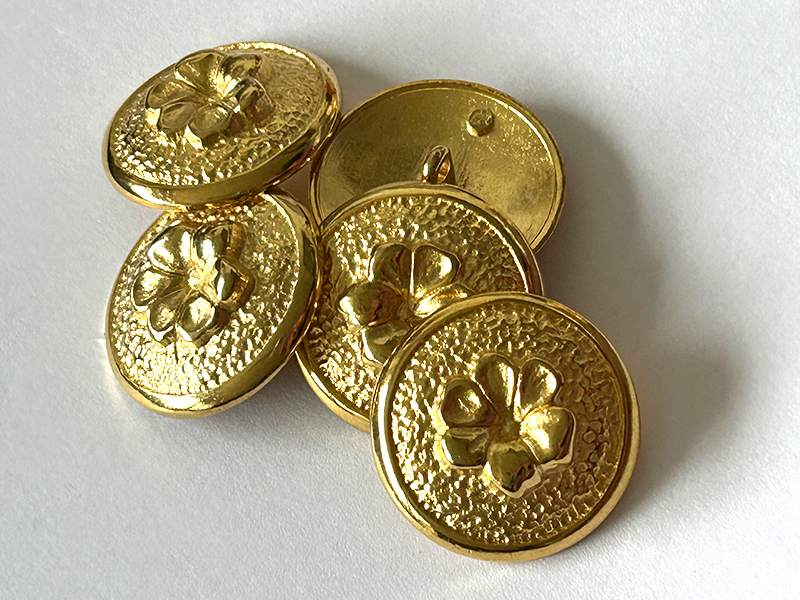 Goldfarbener Metallknopf mit plastischer Blüte