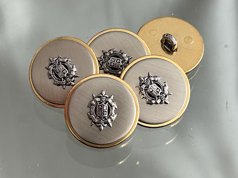 Silberfarbene Metallknöpfe mit Wappenmotiv und goldfarbenem Rand – klassische Blazerknöpfe