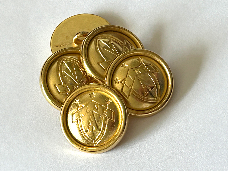 Goldfarbene Metallknöpfe mit Wappen und hohem Rand