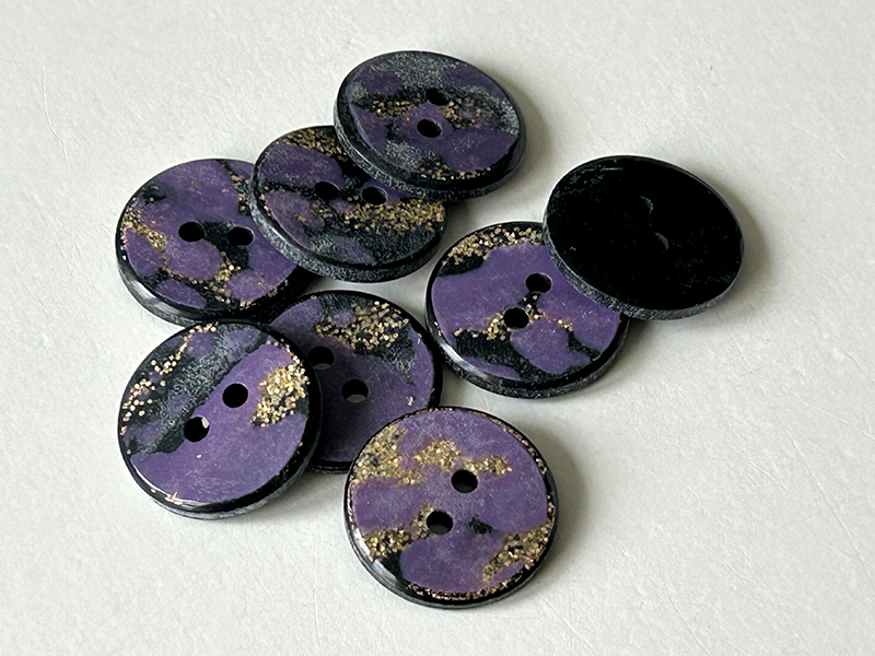 Hübsche Kunststoffknöpfe in schwarz und lila mit goldfarbenem Glitter
